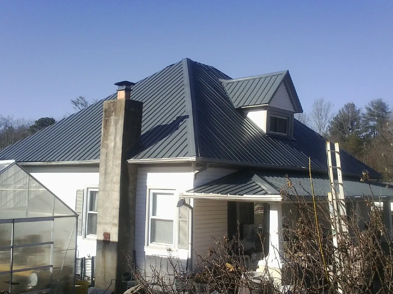 Dark blue standing seam metal roof on a white farmhouse with dormer — Slate & Tile Roof Repair by Roofing Brothers in Thurmont