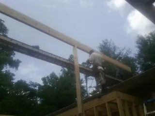 Carpenter setting a ridge beam over a new addition frame — Ice Dam Removal by Roofing Brothers in Thurmont