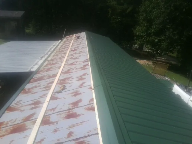 Old rusted panels beside newly installed green metal roofing — Wind Damage Roof Repair by Roofing Brothers in Thurmont