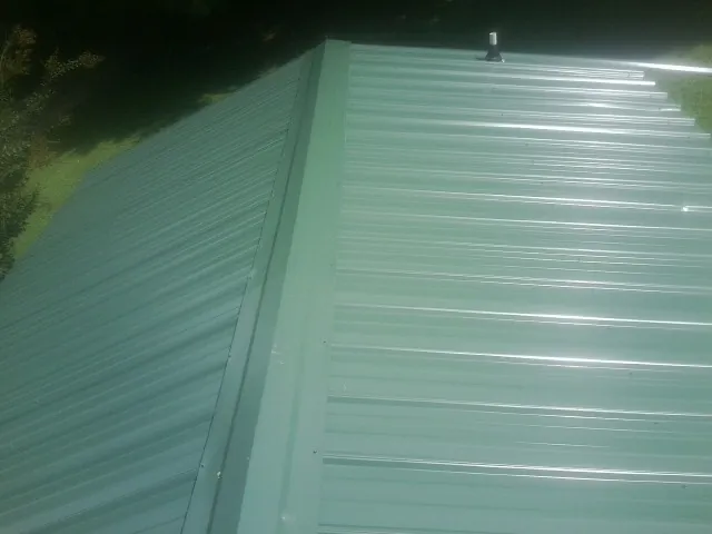 New green metal panels meeting at the ridge of a roof — Flat Roof Repair work by our crew in Thurmont