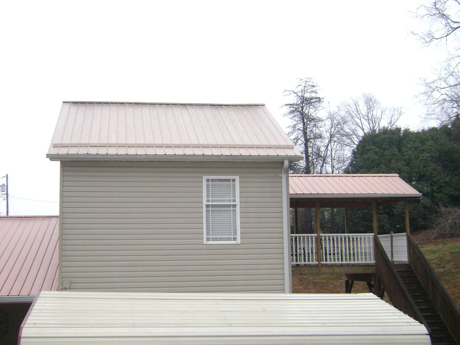Tan metal roofs on a two story addition and attached porch, from a Roof Replacement job in Thurmont