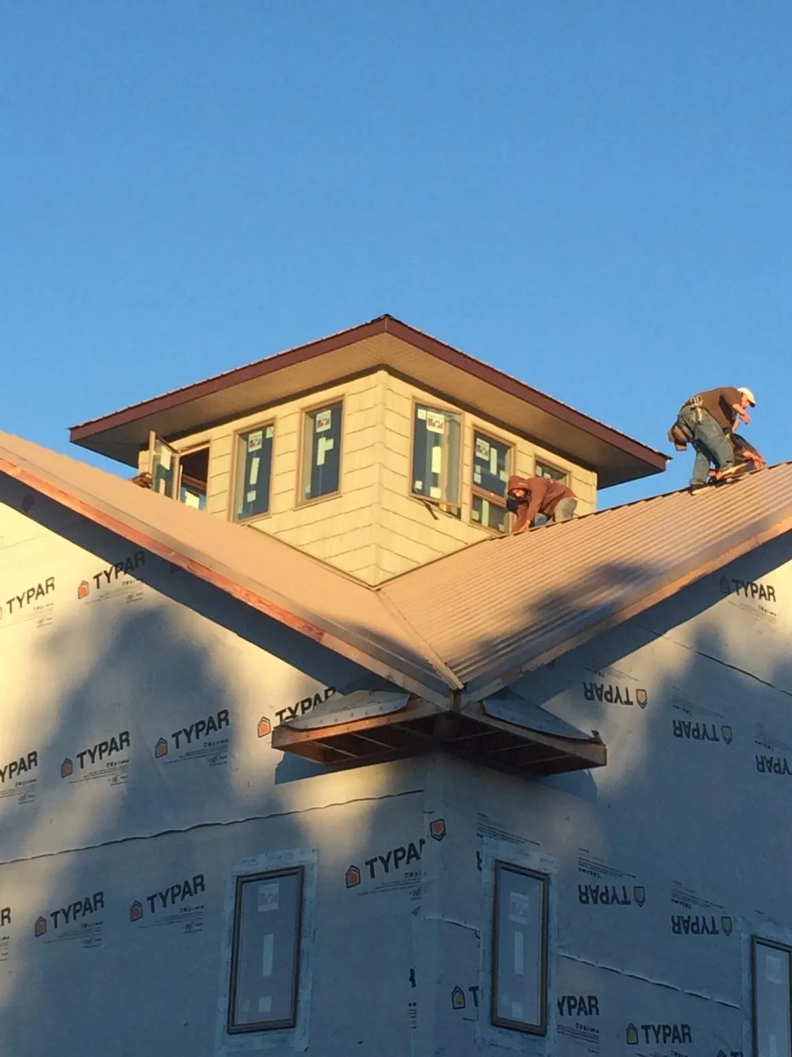 Roofers working around a rooftop cupola on a new metal roof at sunset — Roof Waterproofing in Thurmont by Roofing Brothers